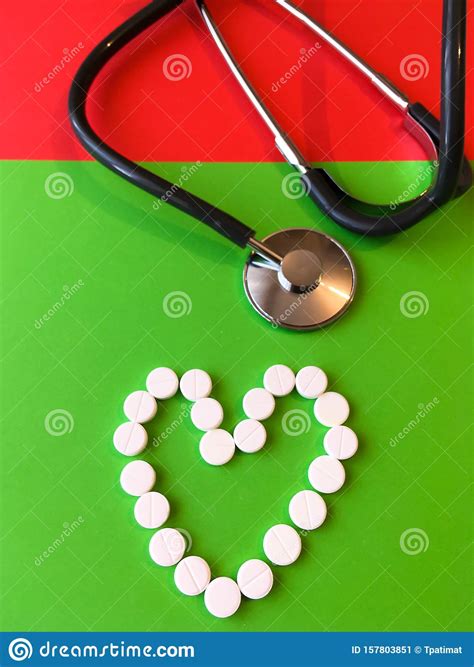 Medical Stethoscope With Pills In The Shape Of A Heart On A Green And