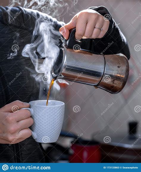Closeup Of Female Adult Hands Pouring Hot Coffee In A White Cup Stock