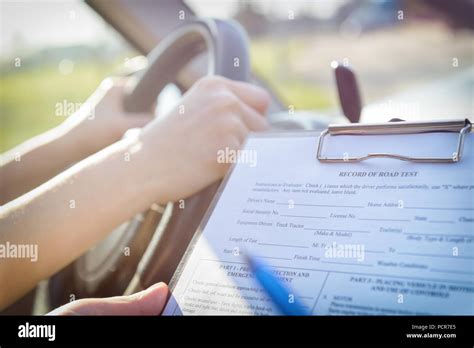 Examiner Filling In Drivers License Road Test Form Sitting With Her