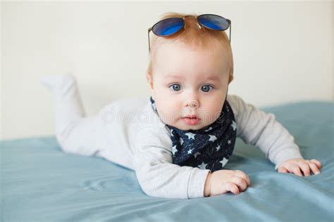 Little Funny Baby Boy With Big Blue Eyes And Sunglasses On His Head