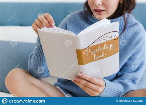 Girl In A Blue Sweater Reading A Book On Psychology Sitting On The Bed In A Cozy Interior Stock