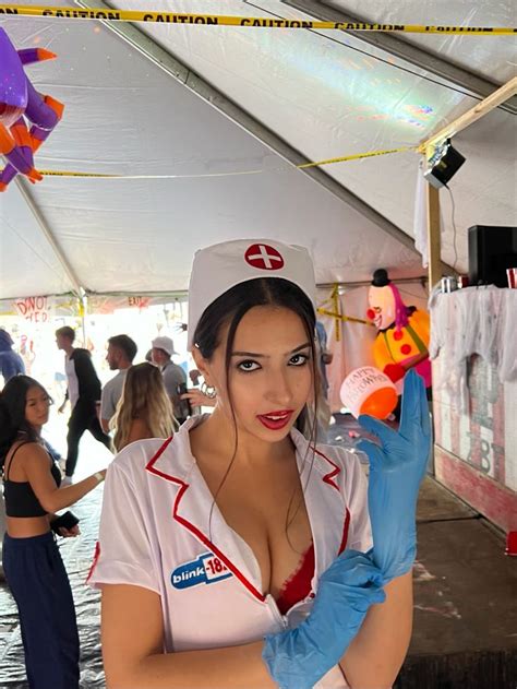 A Woman Dressed As Nurse Holding An Item In One Hand And Gloves On The