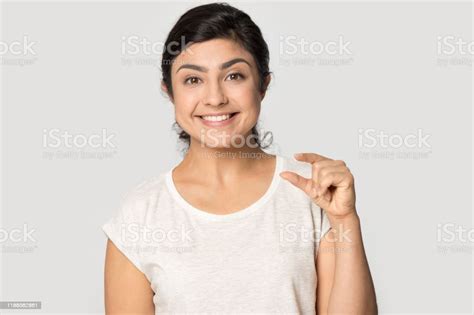 Smiling Satisfied Indian Girl Showing Little Size Gesture With Fingers