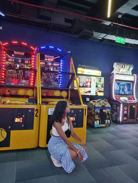 A Woman Sitting On The Floor In Front Of Some Arcade Machines