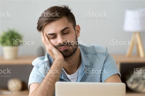 Bored Sleepy Man Feels Drowsy Resting On Hand Near Laptop Stock Photo