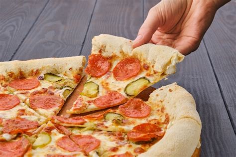 Premium Photo Hand Taking Slice Of Pizza Pepperoni From Plate