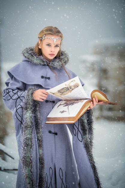 Портрет сказочной эльфийки с волшебной книгой в руках на фоне зимней природы и волшебной
