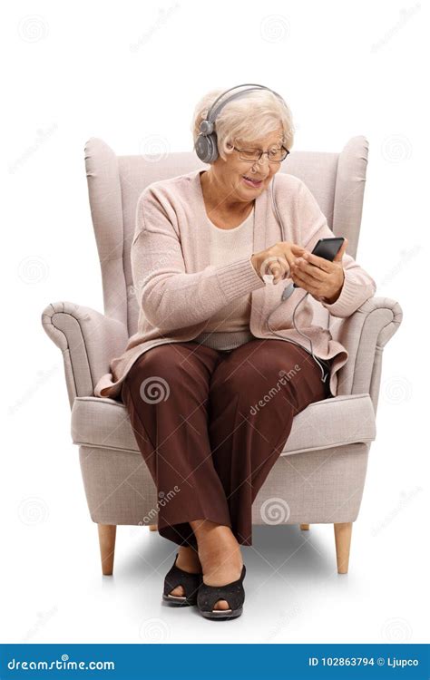 Elderly Woman Sitting In An Armchair And Listening To Music On A Stock
