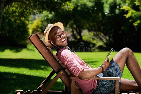 Happy Young Man Relaxing On Chair Outdoors With Digital Tablet Stock
