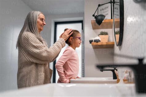 A Senior Grandmother And Granddaughter Standing Indoors In Bathroom