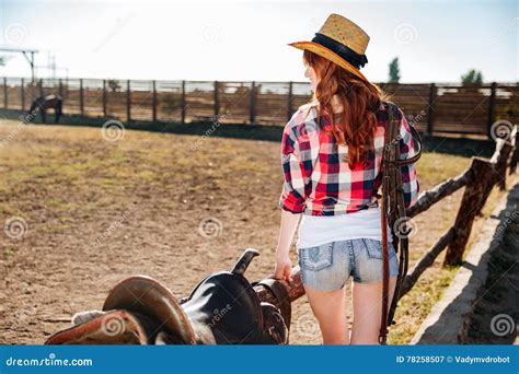 Young Cowgirl In Straw Hat Preparing Saddle For A Ride Stock Image