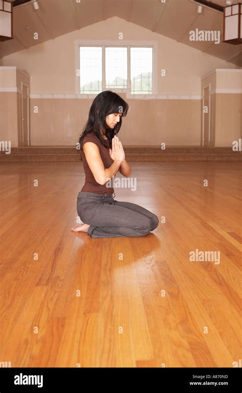 Young Woman In Prayer Sitting On The Fkloor On Her Knees In An Empty