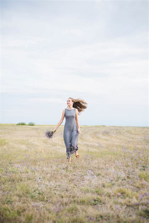 Young Woman Running In A Field And Holding Flower Bouquet By Stocksy Contributor Jovana