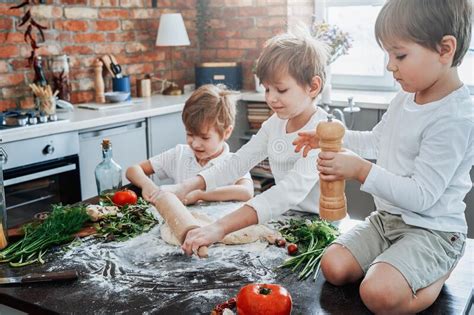 Modern Kitchen And Three Youth Boys Cooking Some Food Stock Photo