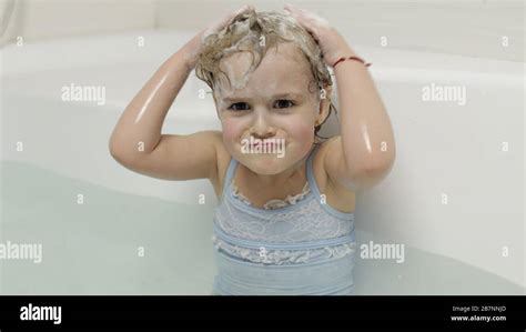 Attractive Four Years Old Girl Takes A Bath With Bath Foam In Swimwear Washes Her Head Wet