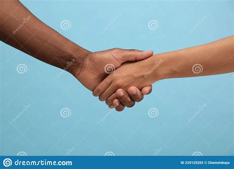 Woman And African American Man Shaking Hands On Light Blue Background