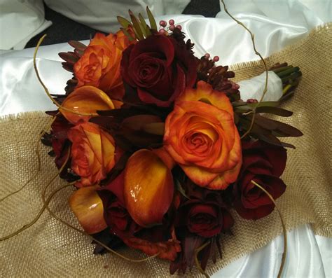 Blush magnolias with pink centers adorn this natural looking brown stem. Fall wedding bouquet with high magic and red roses, cala ...