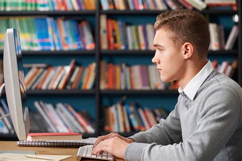 Male Teenage Student Working At Computer In Library • Elc