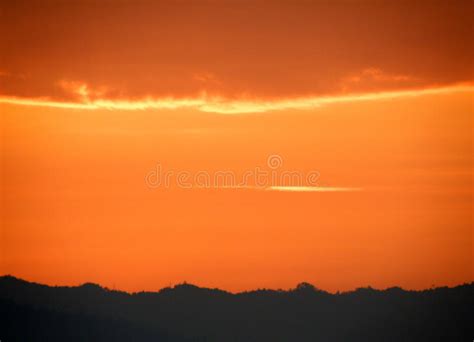 Orange Gradation Of Sunset Cloudy Sky Over The Silhouette Of Mountain