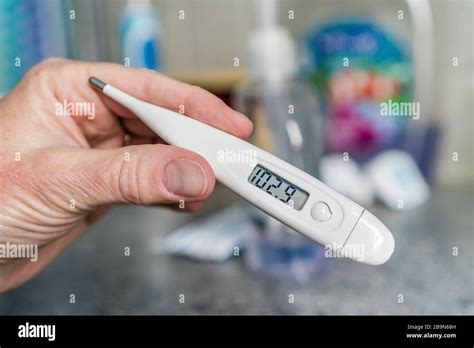 Close Up Of Hand Holding Thermometer Measuring A High Fever Stock Photo