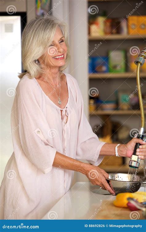 Smiling Older Woman Washing Vegetables In Kitchen Stock Photo Image