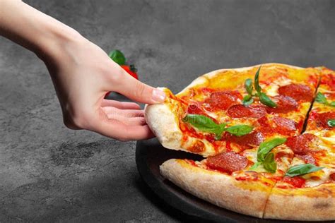 Female Hand Take Slice Of Pepperoni Pizza With Basil Stock Image