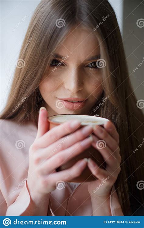 Beautiful Girl Is Drinking Coffee And Smiling While Sitting At The Cafe