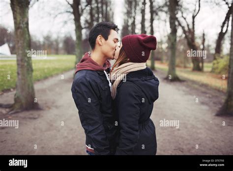 junges liebespaar küssen im freien im park gemischte rassen mann und frau teenager liebe