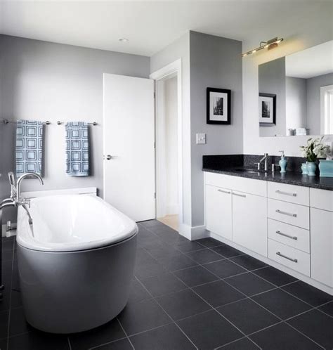 The scalloped tiles in this bathroom helps soften the dark gray floor. Bathroom with dark grey floor, light grey walls, white ...