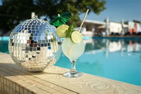 Tasty Refreshing Cocktail And Shiny Disco Ball On Edge Of Swimming Pool Party Items Stock Image