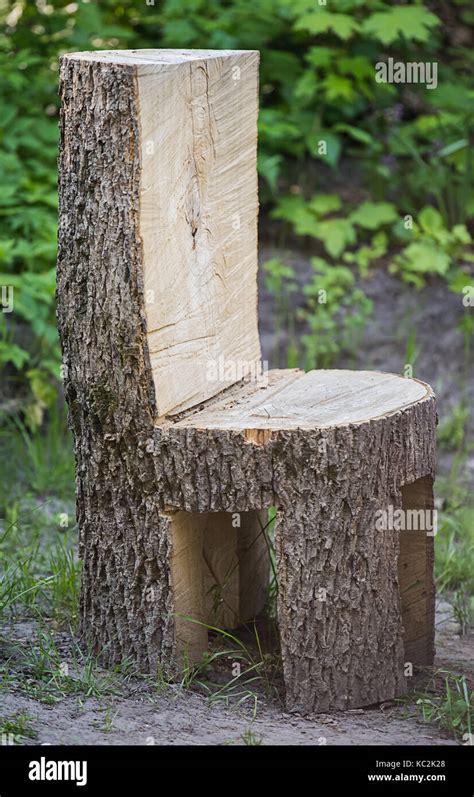 chunky ugly chair made of the whole tree trunk is standing outdoor on the ground unfocused