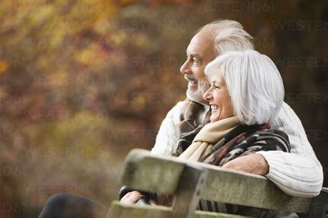 Older Couple Sitting On Park Bench Stock Photo