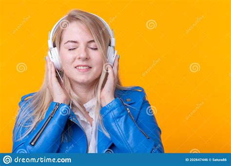 Portrait Of Cute Positive Young Blonde Girl Listening To Favorite Music In Headphones In Blue