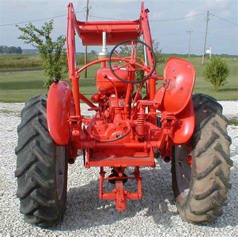 An Old Red Farmall Tractor Parked On Gravel