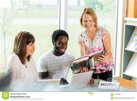 Happy Librarian Assisting Students In Library Stock Photo Image Of