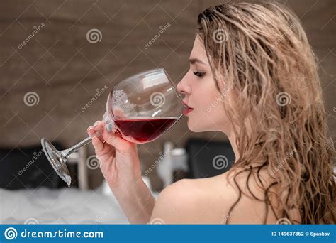Attractive Blonde Woman Lying In Bathtub In Foam In Hotel Drinking Red