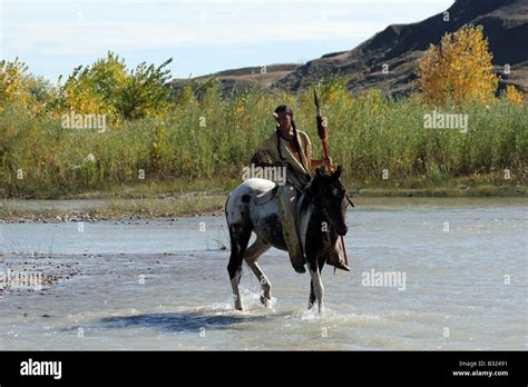 A Native American Sioux Indian On Horseback Riding Across A Stream In