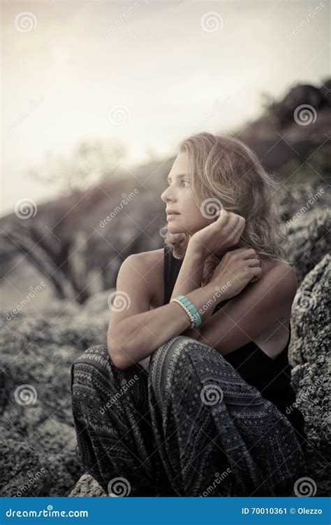 Beautiful Young Woman Sitting On The Rocks At Sunset Stock Image