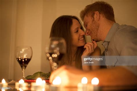 Couple Enjoying A Glass Of Red Wine By Candlelight Face To Face Smiling