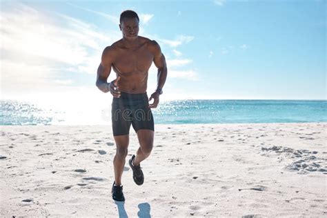 Fit Young Black Man Running And Jogging On Sand At The Beach In The