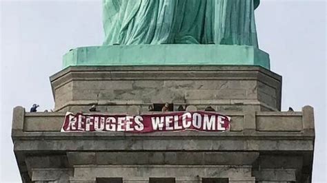 refugees welcome banner hung on statue of liberty in new york bbc news