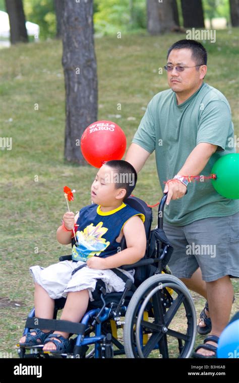 Handicapped Physically Challenged Boy Being Pushed By Dad In Wheelchair