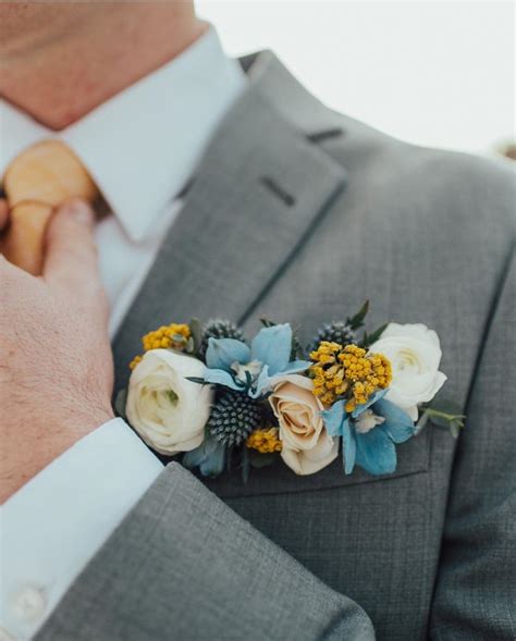 Each collection is developed and inspired by fine art, commercial and naïve design, as well as the brain's reaction to color, movement, and contrast. Pocket Square Boutonniere with white spray roses, blue thistle, light blue delphinium, and ...