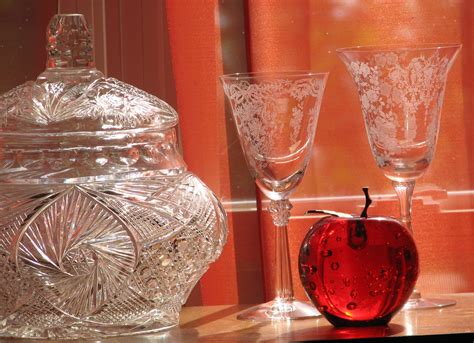 Two Wine Glasses And An Apple Sit On A Table Next To A Glass Jar With Lace Designs