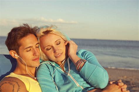 Couple Relaxing While Listening Music On Headphone At Beach Stock Photo