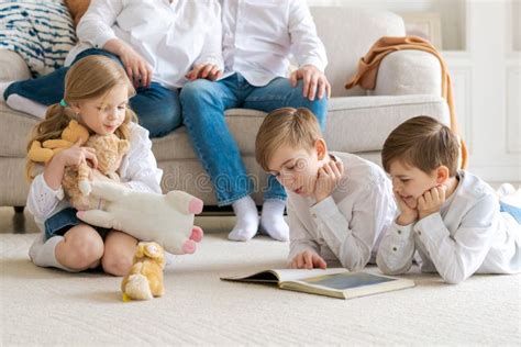 Happy Caucasian Parents Sit Relax On Sofa And Watch As Busy Little