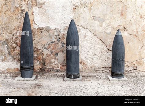 Dark Large Caliber Artillery Projectiles Stand Near Grungy Wall In A