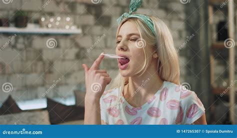 portrait of a lady with blonde hair eating very sensuality a gum in front of the camera and make