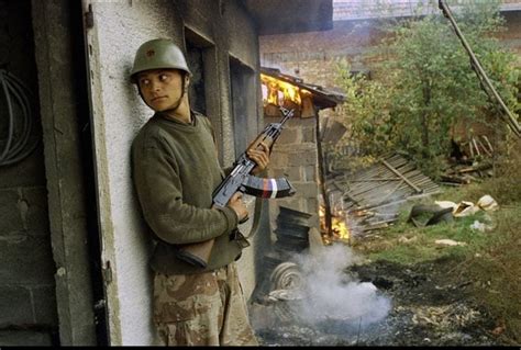 A Vrsarmy Of Republika Srpska Soldier Takes Cover By A Burning House