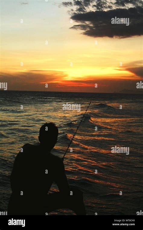 Silhouette Man Fishing In Sea At Sunset Stock Photo Alamy